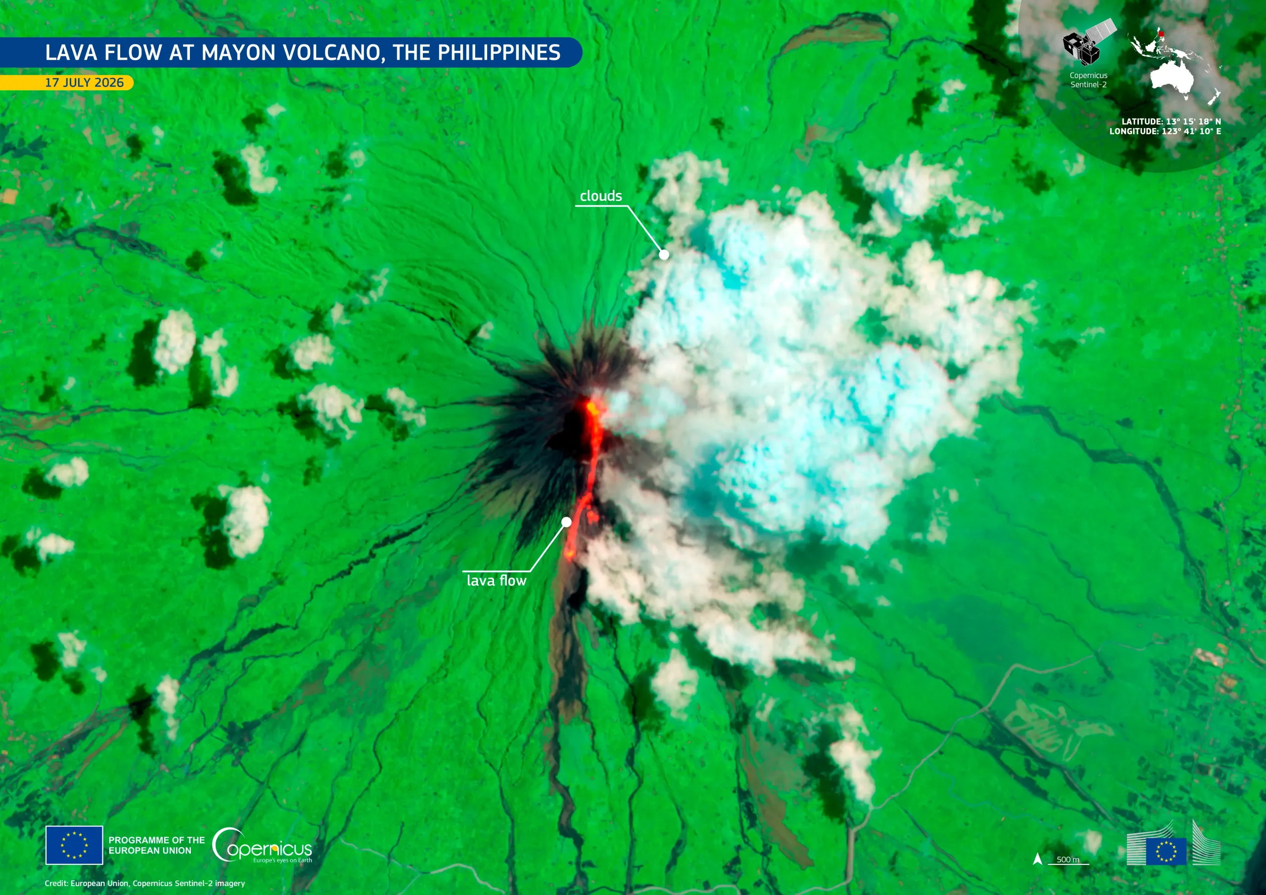 Satellite image of a volcano eruption with lava flow visible in red, smoke in white and light blue, and surrounding vegetation in bright green.