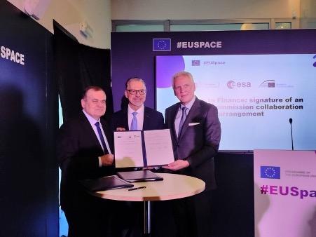 Three men in suits stand together holding signed documents at an EU Space collaboration event.