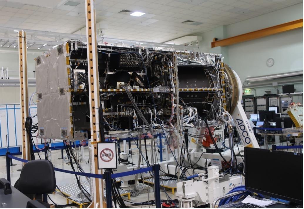 A large, complex scientific instrument with numerous wires and components sits in a clean, organized lab. A "No Entry" sign is visible in the foreground.