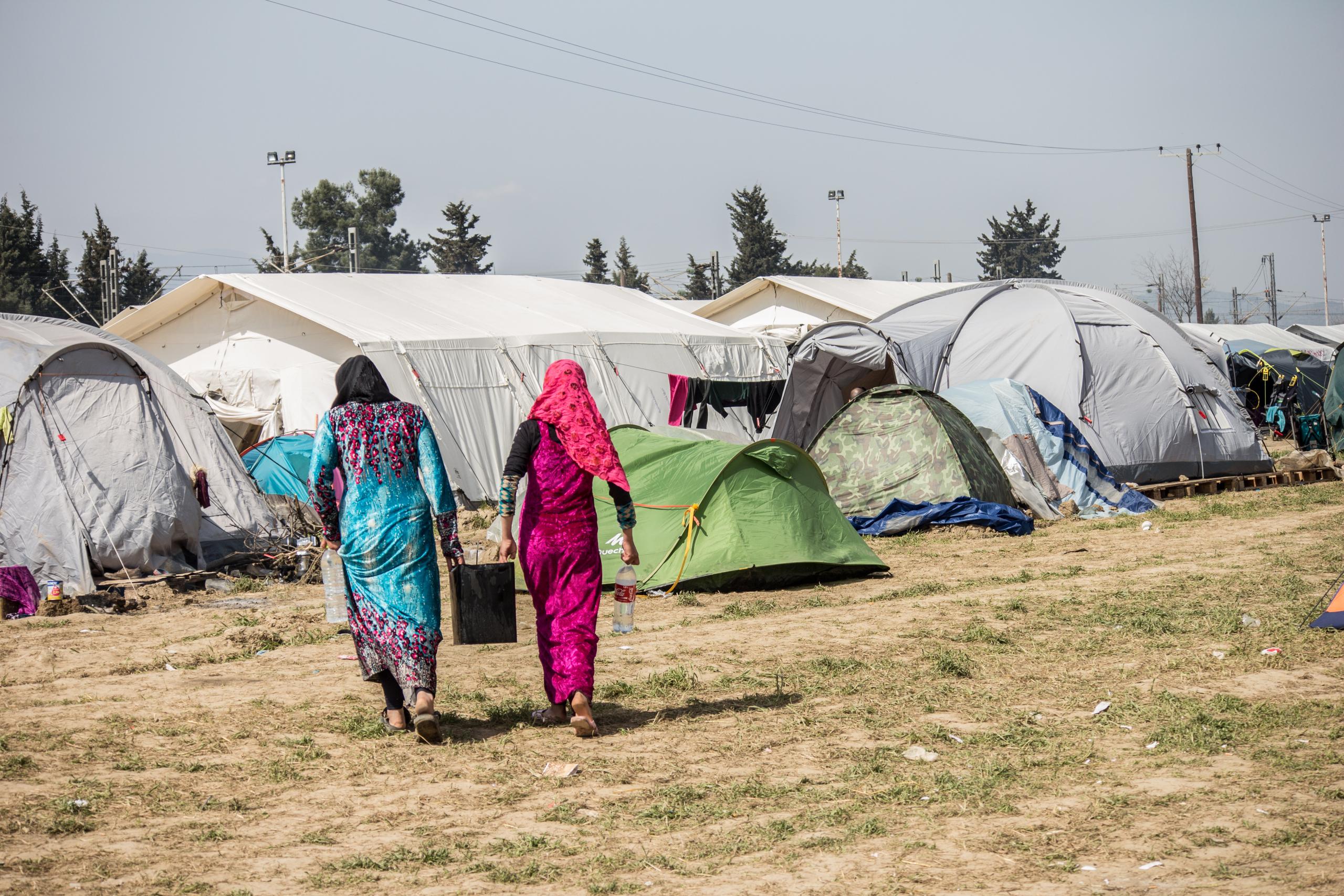 Two women stroll past a row of tents, enjoying the outdoor atmosphere and the vibrant surroundings.