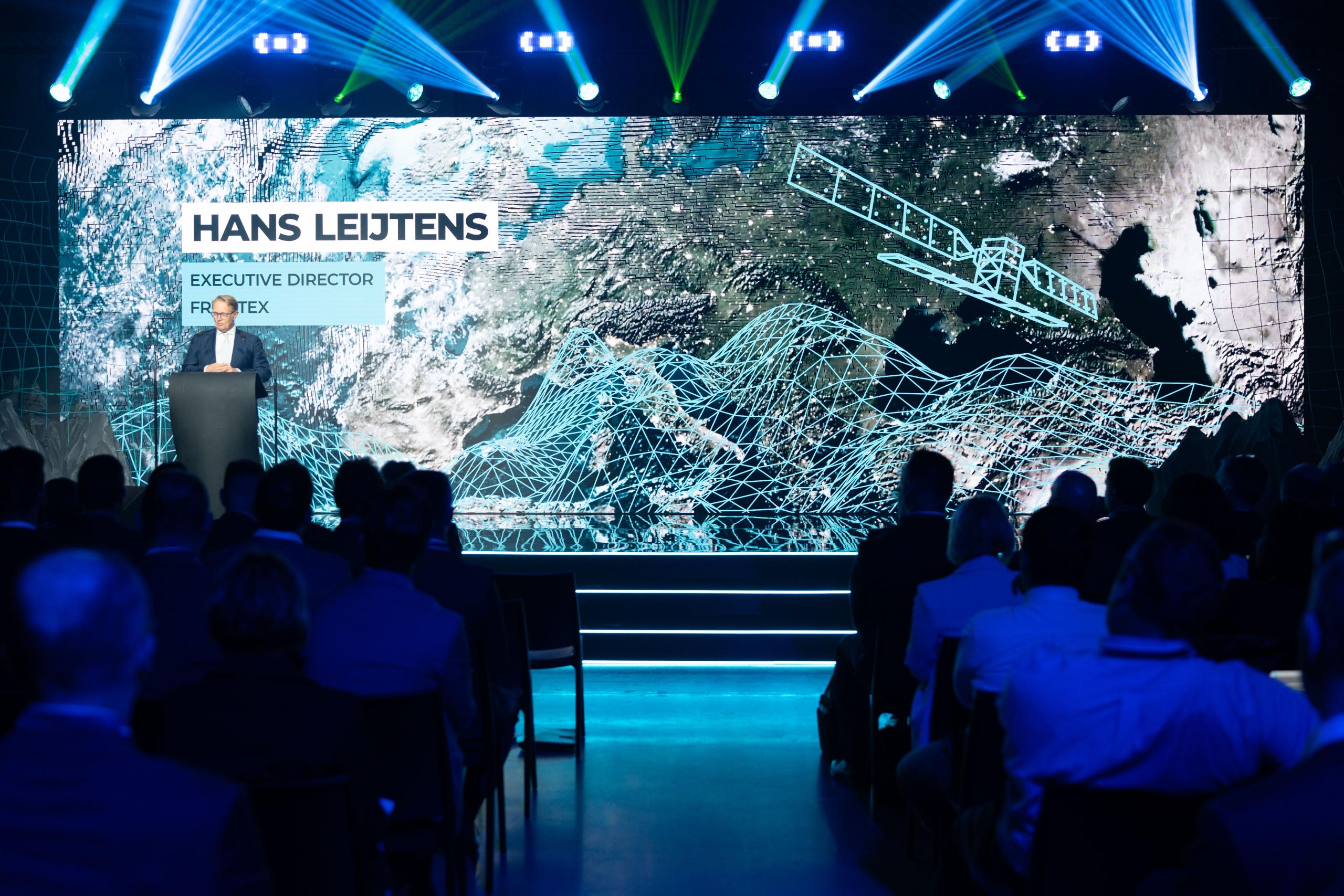 Hans Leijtens, Executive Director of Frontex, delivers a keynote speech at the “10 Years of Copernicus at Frontex” event. He stands at a podium in front of a large screen displaying a satellite image of Europe overlaid with digital 3D grid graphics and...