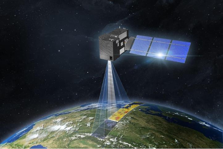 The image is an artist’s impression of a CO2M satellite in space. The satellite has a rectangular body with solar panels extending from one side. It is positioned above Earth, with a visible beam projecting downward, indicating the satellite's monitori...