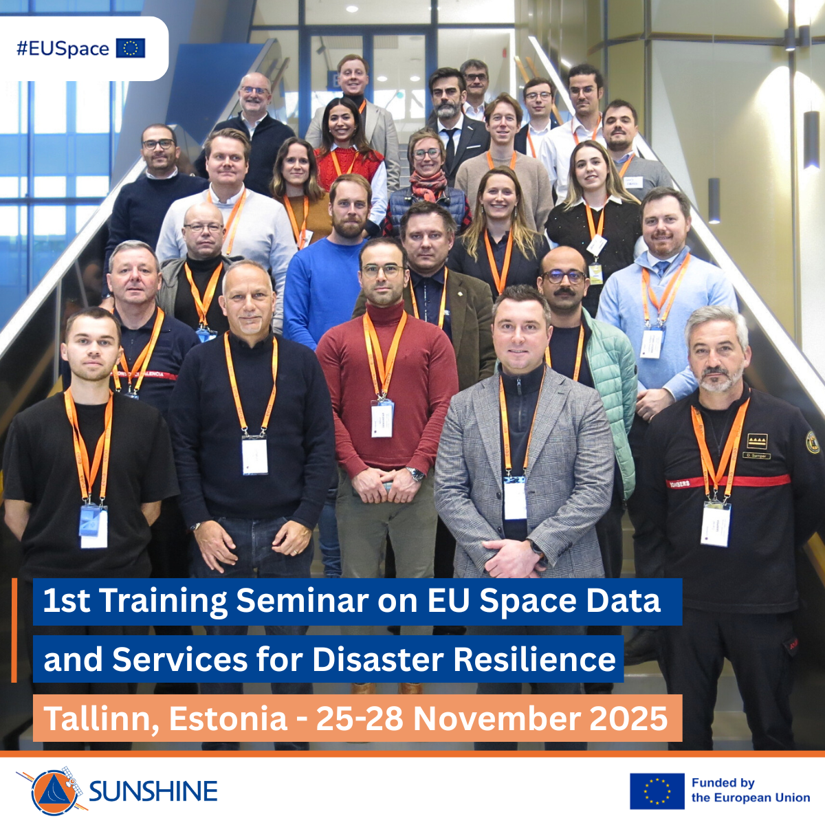 Group photo of approximately 30 participants wearing conference badges and orange lanyards, standing on indoor stairs. A banner reads: ‘1st Training Seminar on EU Space Data and Services for Disaster Resilience, Tallinn, Estonia – 25–28 November 2025.’...